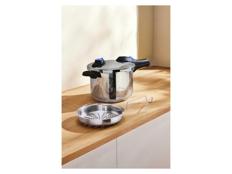 Een roestvrijstalen snelkookpan en stoommandje op een houten aanrecht.