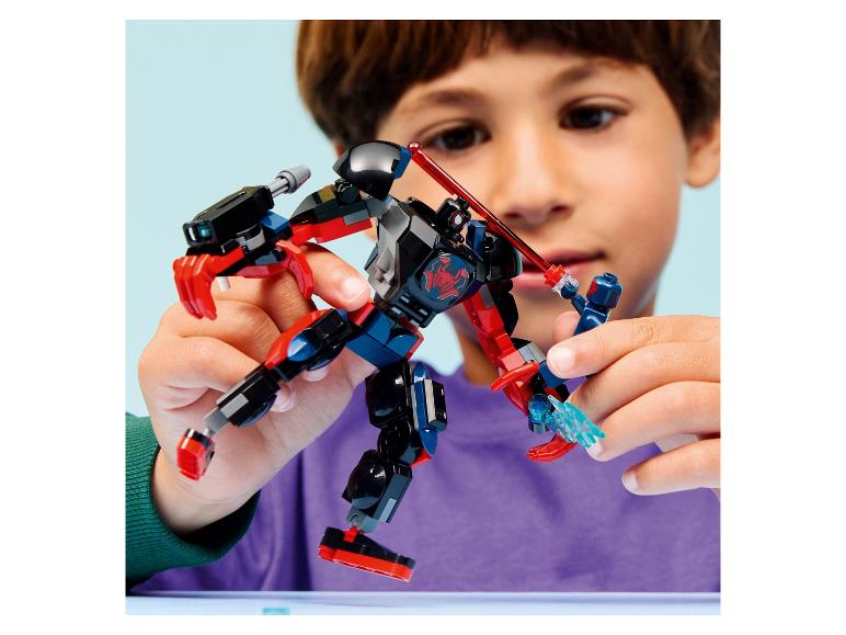 Een kind speelt met een zwart-rood robotspeelgoed en een klein blauw figuurtje.