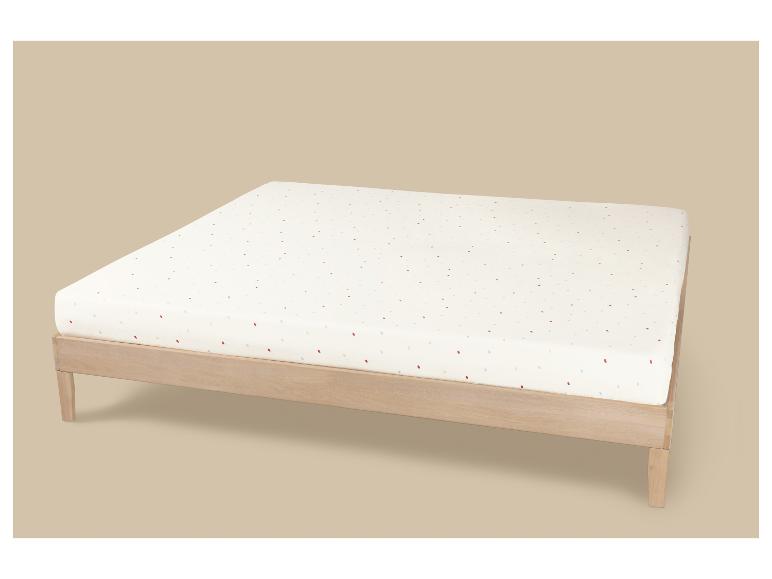 Houten bedframe met een wit matras met kleurrijke stippen.