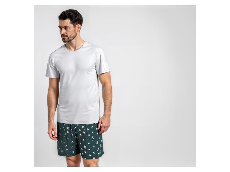 Man in een wit T-shirt en zwemshorts met palmbomenprint.
