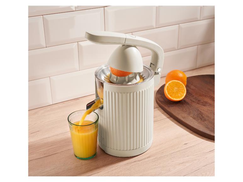 Elektrische citruspers schenkt vers sinaasappelsap in een glas op het aanrecht.