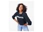 Vrouw in donkerblauwe sweatshirt met „BONJOUR” en jeans