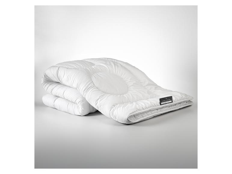 Wit John Cotton dekbed opgevouwen op een grijs oppervlak.