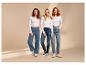 Drie lachende vrouwen in jeans en witte longsleeves.