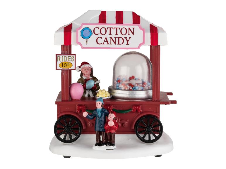 Een feestelijke suikerspinwagen met figuren, een 'Rides 10¢'-bord en een snoepdispenser.