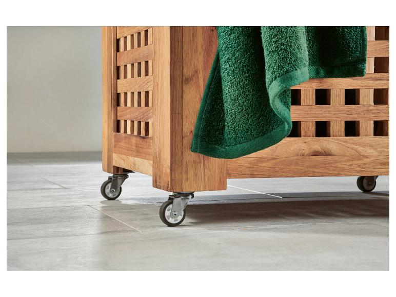Houten wasmand op wieltjes, met een groene handdoek eraan.