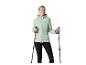 Vrouw in mintgroene gewatteerde jas en zwarte legging, met CRIVIT wandelstokken.