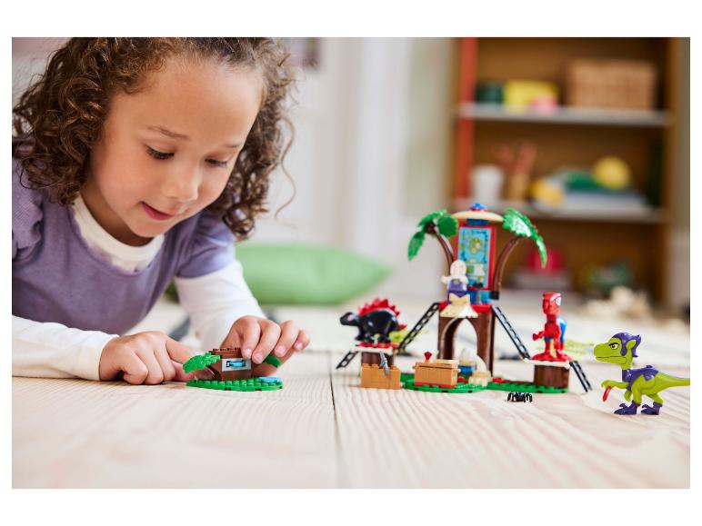 Een jong meisje speelt met een LEGO DUPLO boomhutset en dinosaurusfiguren.