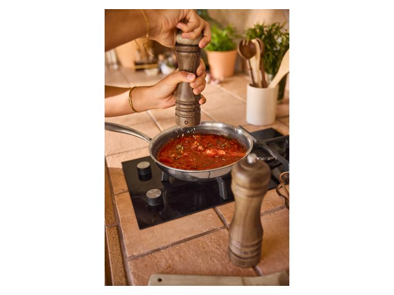 Tomatensaus wordt bereid; houten pepermolens.