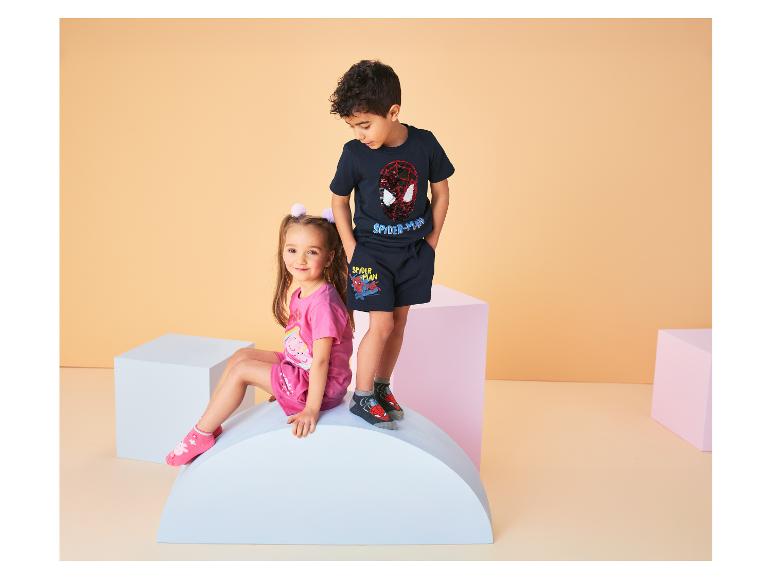 Twee kinderen, een meisje en een jongen, dragen T-shirts en shorts met stripfiguren.