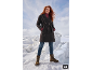 Vrouw in donkere jas, rode coltrui, jeans en bruine laarzen in een sneeuwlandschap.