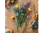 Kleurrijk boeket van bouwsteenbloemen op een gevlochten kleed met tuiniersaccessoires.
