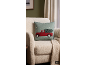 Groen kussen met rode kersttruck en boom op een beige fauteuil.