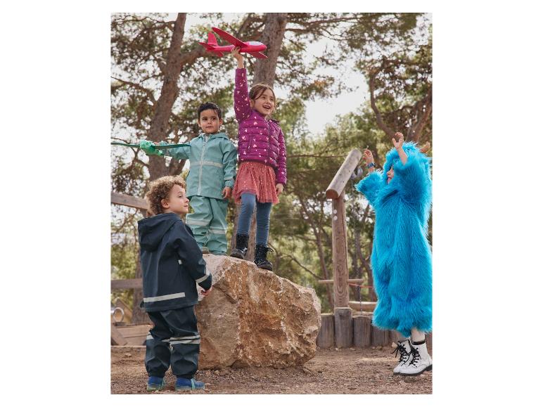 Kinderen spelen in een park en dragen Reima regenkleding en andere kleding.