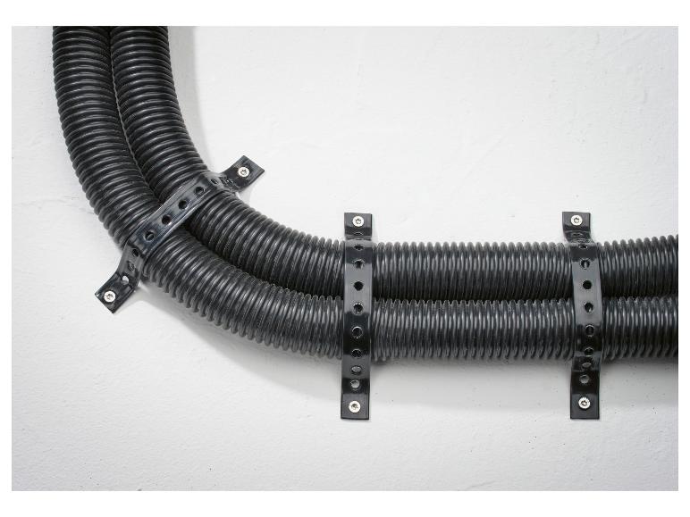 Zwarte geribbelde buizen bevestigd aan een witte muur met plastic banden