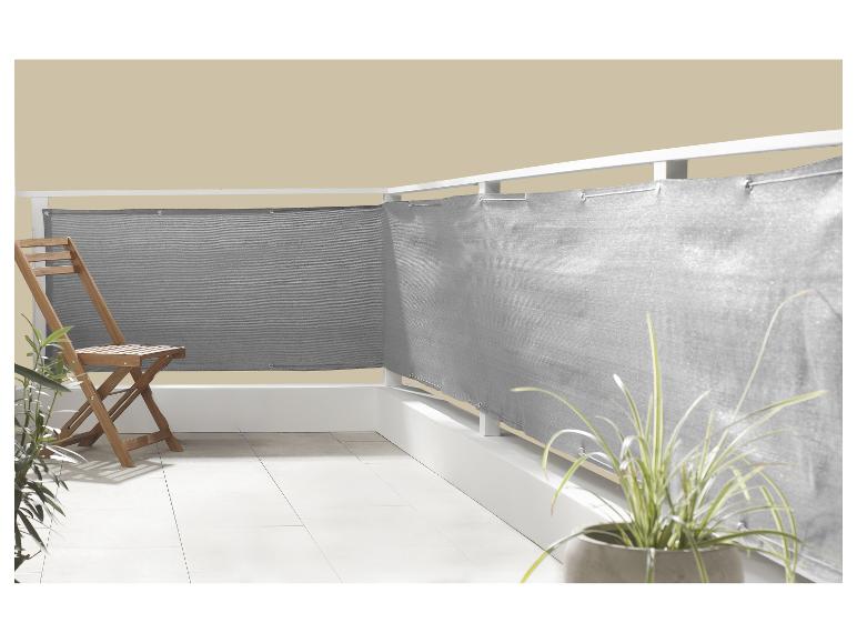 Balkon met grijs privacyscherm, houten stoel en potplanten.