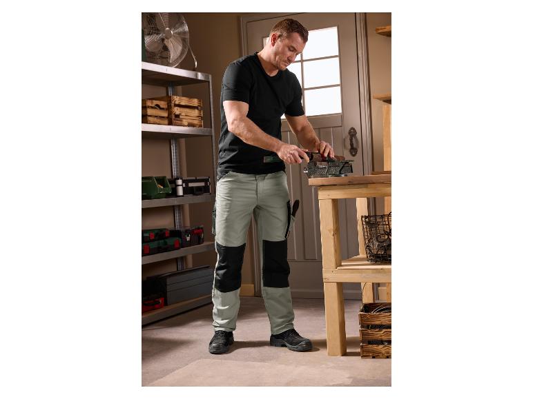 Man in PARKSIDE® werbroek die hout bewerkt in een werkplaats.