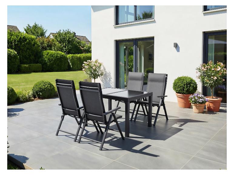 Tuinmeubelset: tafel en vier stoelen op een terras, omringd door groen.