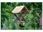 Vogelvoederhuisje met twee vogels, hangend tussen bomen en planten.