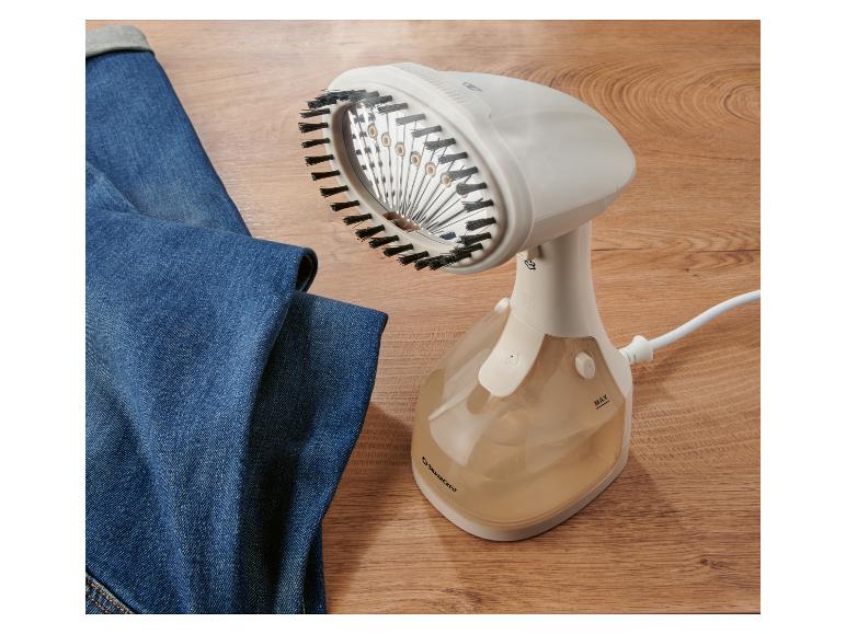 Een witte handstomer met borstel, naast een blauwe spijkerbroek.