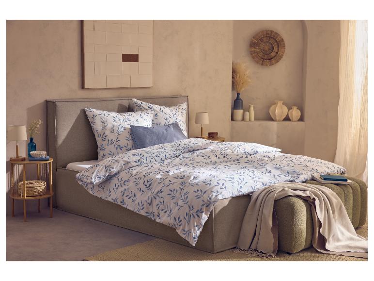 Slaapkamer met tweepersoonsbed, blauw-wit beddengoed met patroon en houten nachtkastje.