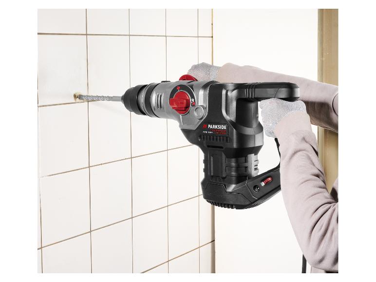 Persoon boort een gat in een witte tegel met een Parkside Performance SDS Max boorhamer.