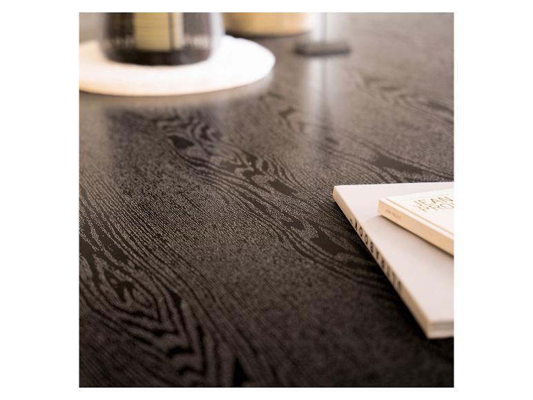 Donkere houten tafel met boeken en een glas op een onderzetter.