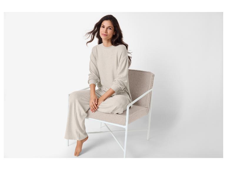 Vrouw in beige loungewear zit op een beige fauteuil.