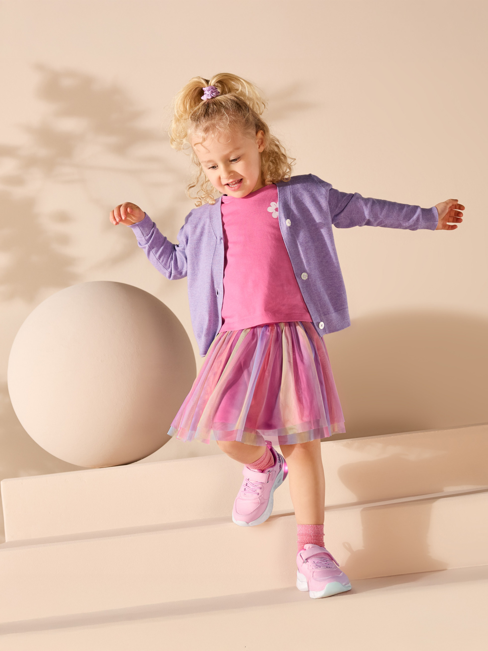 Meisje in roze T-shirt, paars vest en kleurrijke tule rok.