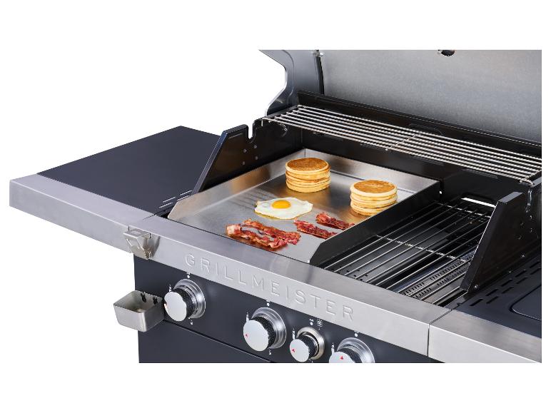 Barbecue met bakplaat waarop pannenkoeken, eieren en spek worden gebakken.