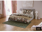 Slaapkamer met bed, bloemenbeddengoed, groen vloerkleed en roze gordijnen.