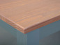 Een houten tafelblad met een lichtblauwe onderkant.