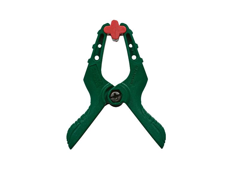 Een groene veerklem met een rood handvat, op een witte achtergrond.