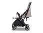 Zijaanzicht van een beige en zwarte kinderwagen met opbergmand.