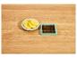 Gesneden aardappelen op een wit bord en een groene aardappelsnijder op een houten tafel.