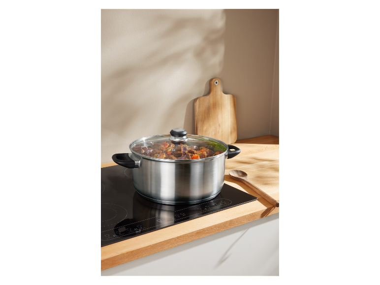 Een roestvrijstalen pan met eten kookt op een inductiekookplaat.