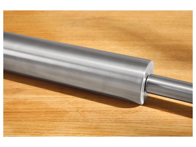 Metalen deegroller op een houten plank