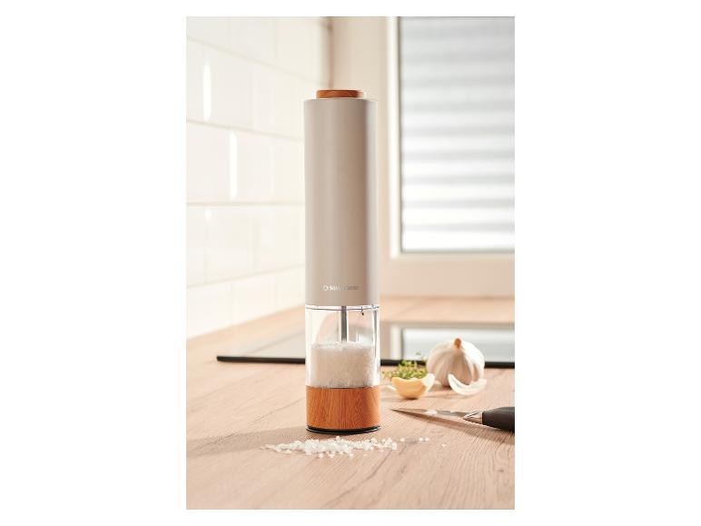 Zoutmolen op een houten aanrecht met knoflook en kruiden.