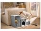 Hond beklimt grijze huisdierentrap met ingebouwd bed, naast een beige bank in een woonkamer.