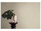 Een plant in een lichtroze vaas op een donkere houten kruk met een decoratief ei.