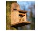 Houten vogelvoederhuisje gevuld met zaden, bevestigd aan een boomstam.