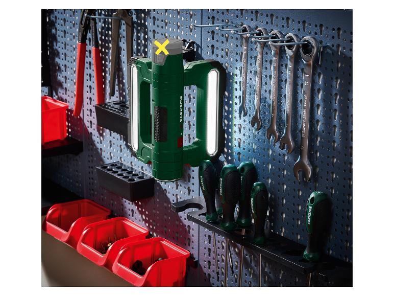 Groene werklamp en gereedschap hangend aan een geperforeerde wand.