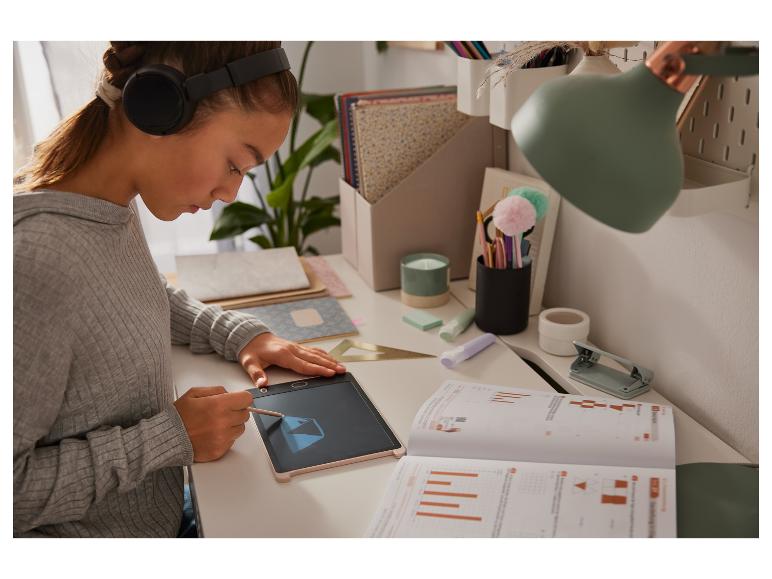 Meisje werkt met een tekentablet en oefenboekjes.