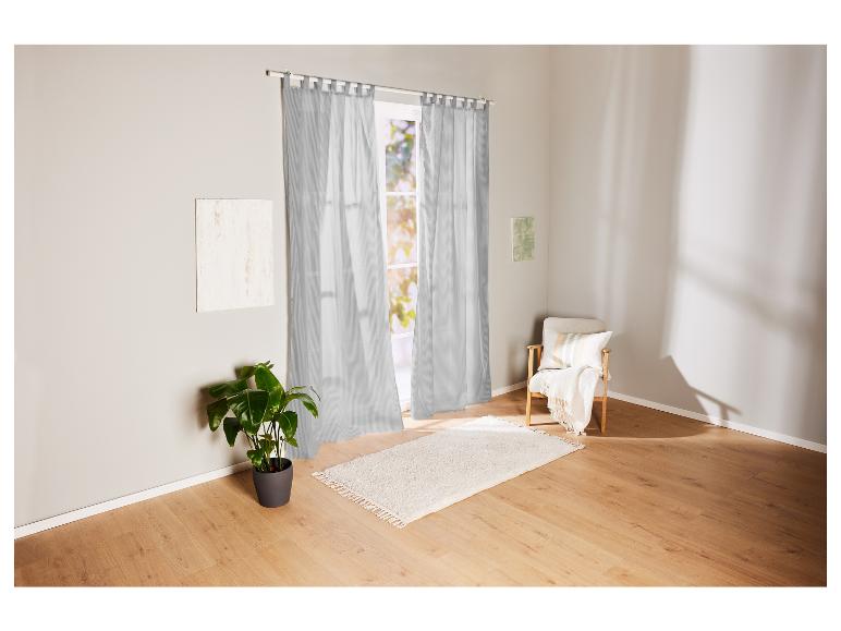 Grijze gestreepte gordijnen, een wit vloerkleed en een houten stoel in een lichte kamer.