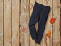 Donkerblauwe leggings op een houten achtergrond met herfstbladeren.