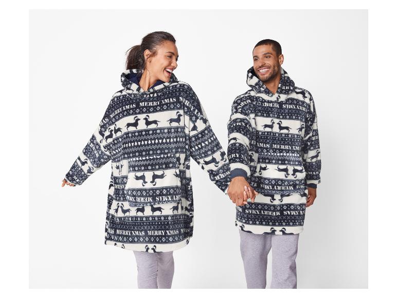 Twee lachende mensen dragen bijpassende pluizige hoodies met kersttekkelprint.
