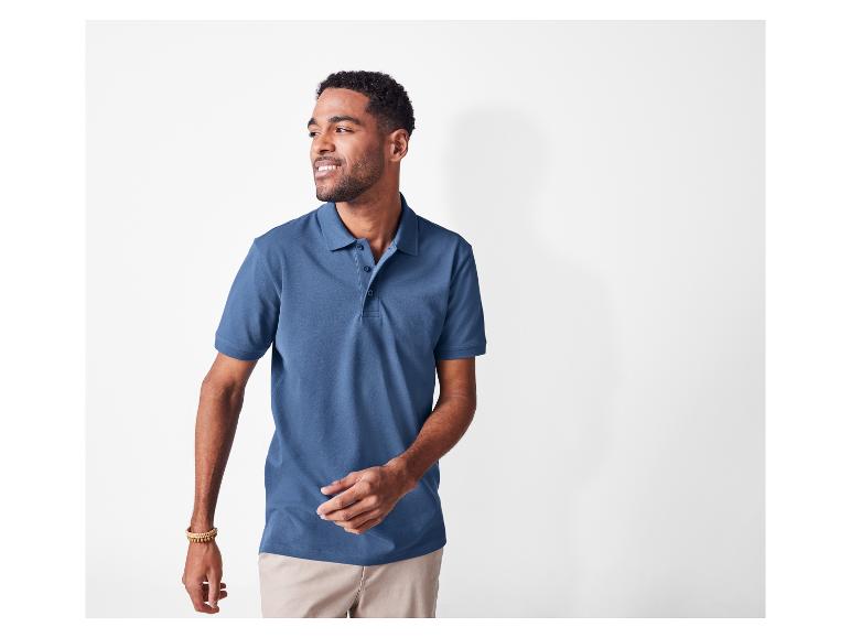 Een man draagt een donkerblauw poloshirt en een beige broek.