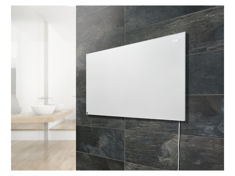 Een witte elektrische radiator hangt aan een donkere betegelde muur in een badkamer.