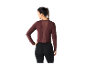Een vrouw draagt een donkerrode blouse met lange mouwen en zwarte leggings.