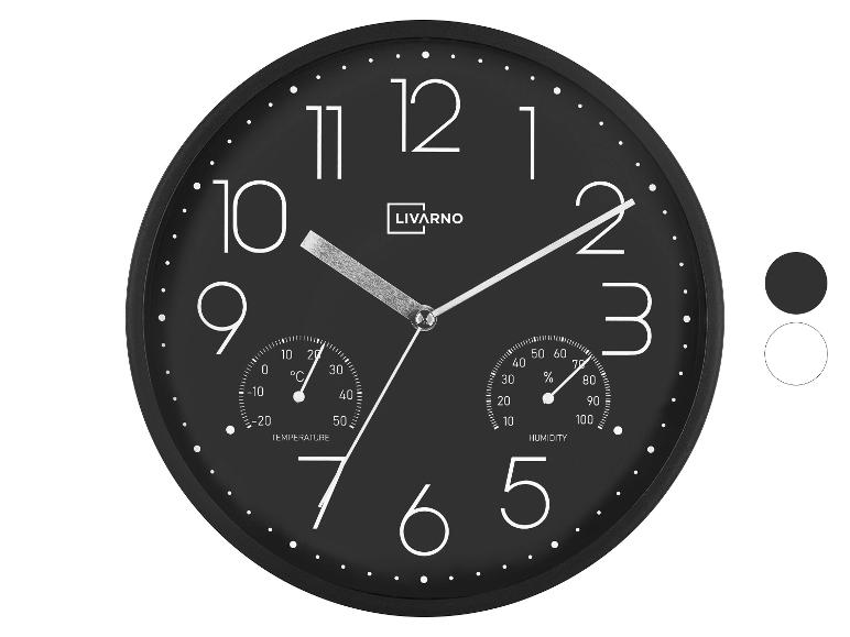 Zwarte wandklok met geïntegreerde thermometer en hygrometer, grote witte cijfers.